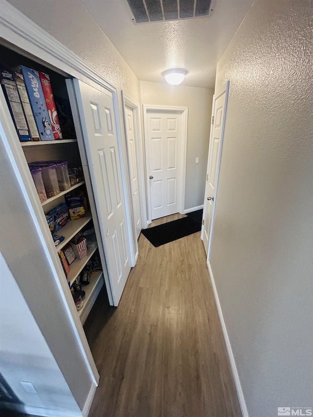 corridor with visible vents, baseboards, and wood finished floors