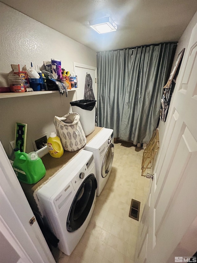 washroom featuring laundry area, washing machine and clothes dryer, visible vents, and light floors