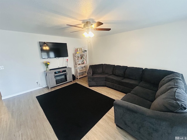 living area featuring baseboards, a ceiling fan, and wood finished floors
