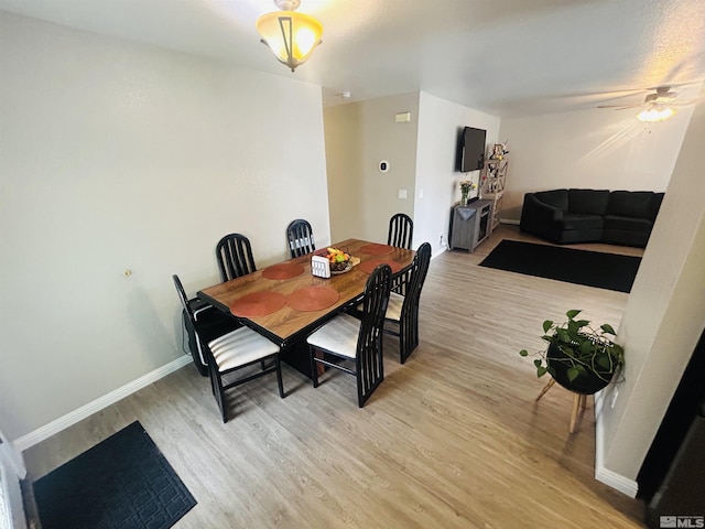 dining area featuring light wood-style flooring, baseboards, and a ceiling fan