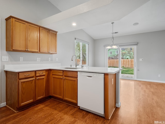 kitchen with dishwasher, a sink, a peninsula, vaulted ceiling, and wood finished floors