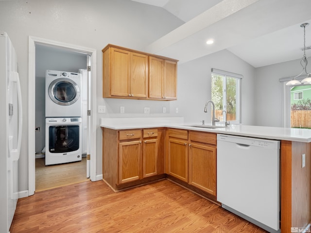 kitchen with a sink, stacked washer and clothes dryer, white appliances, a peninsula, and lofted ceiling