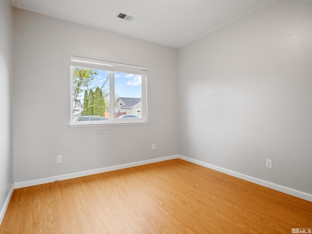 spare room featuring light wood finished floors, baseboards, and visible vents