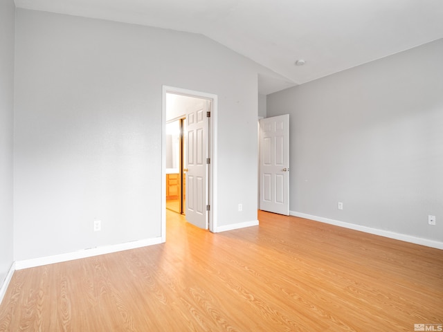 empty room with baseboards, light wood-type flooring, and lofted ceiling