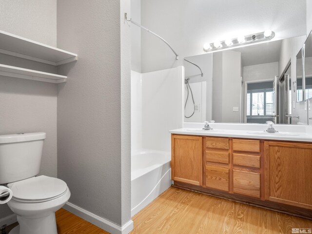 bathroom with a sink, toilet, double vanity, and wood finished floors