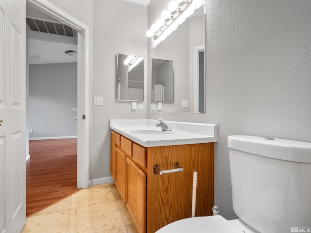 bathroom with baseboards, visible vents, vanity, and toilet
