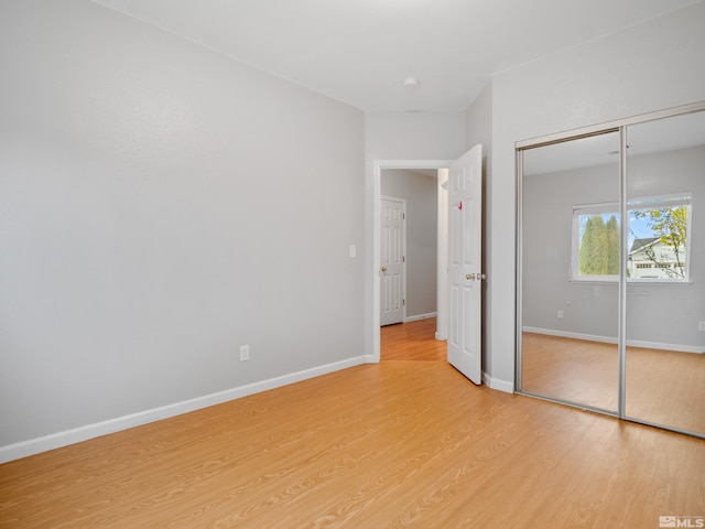 unfurnished bedroom with a closet, baseboards, and light wood-type flooring