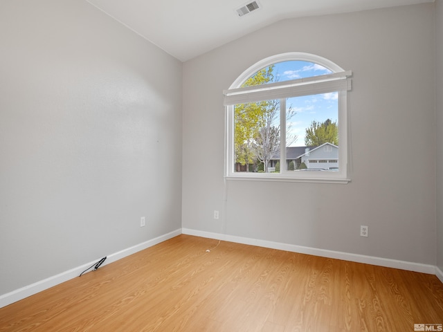 unfurnished room featuring baseboards, visible vents, light wood-type flooring, and vaulted ceiling