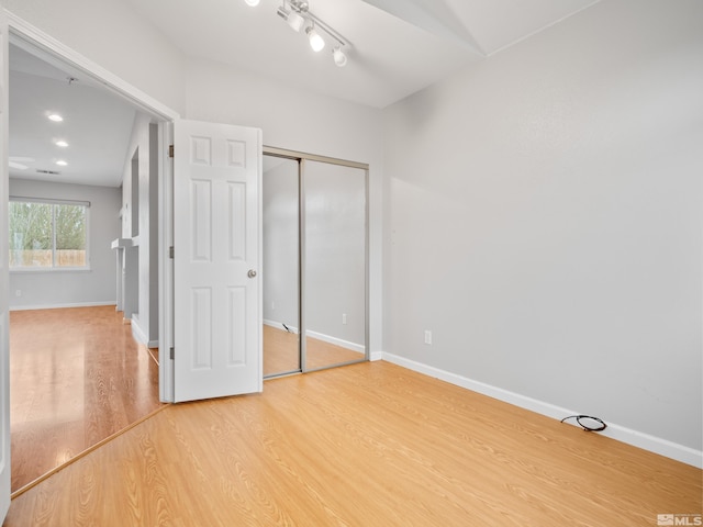 unfurnished bedroom with a closet, light wood-style flooring, and baseboards