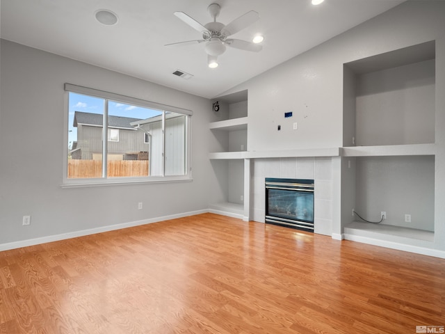 unfurnished living room featuring a fireplace, a ceiling fan, visible vents, wood finished floors, and built in shelves