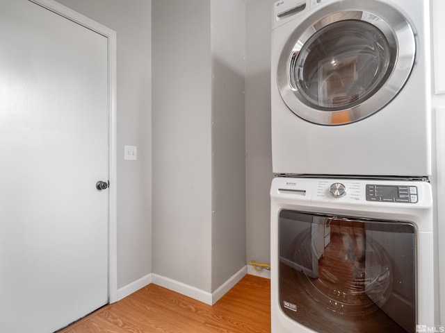 laundry room featuring light wood finished floors, laundry area, baseboards, and stacked washer and clothes dryer