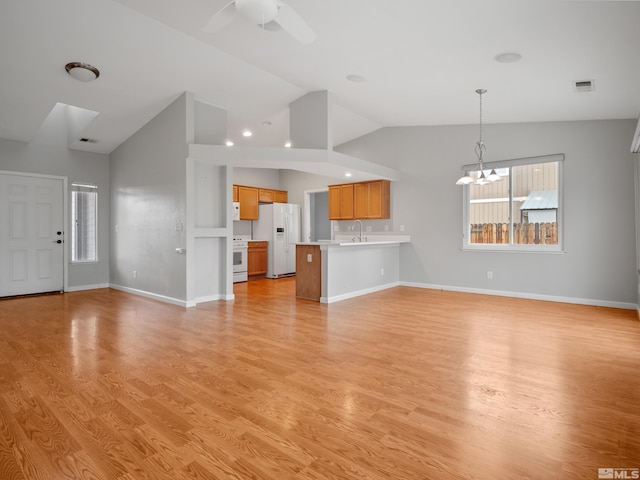 unfurnished living room with light wood finished floors, visible vents, a sink, and vaulted ceiling