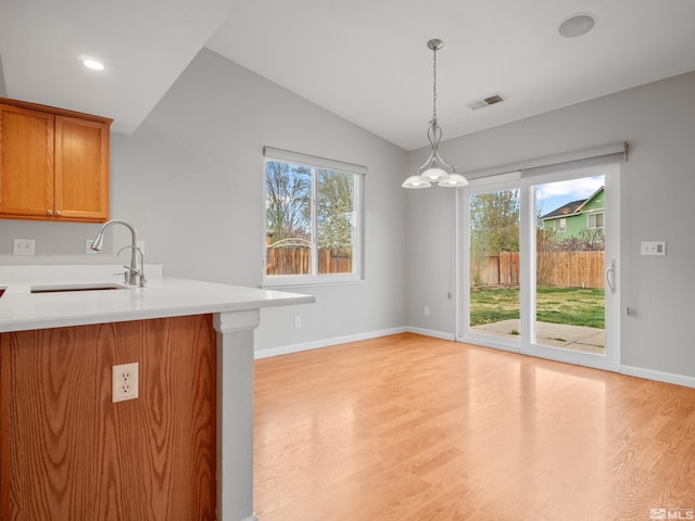 kitchen with vaulted ceiling, visible vents, a healthy amount of sunlight, a sink, and light wood finished floors