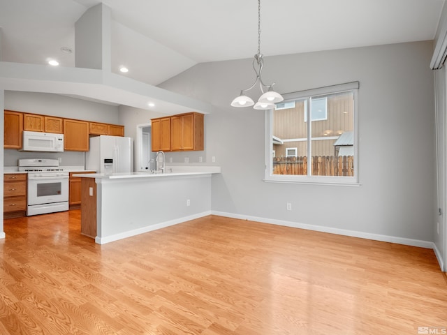 kitchen with brown cabinets, light countertops, light wood finished floors, and white appliances