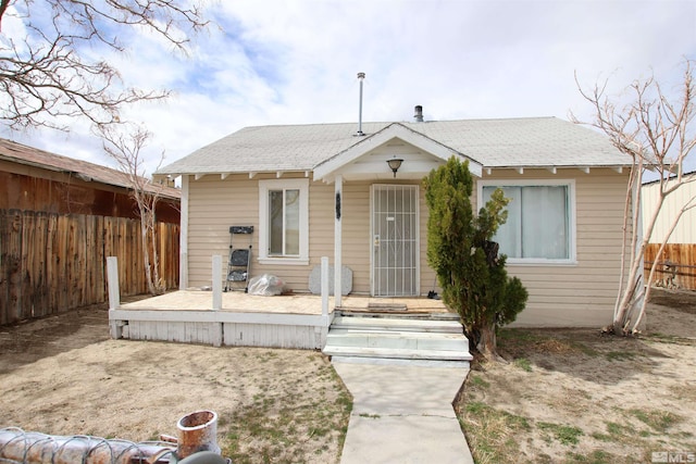bungalow featuring a shingled roof and fence