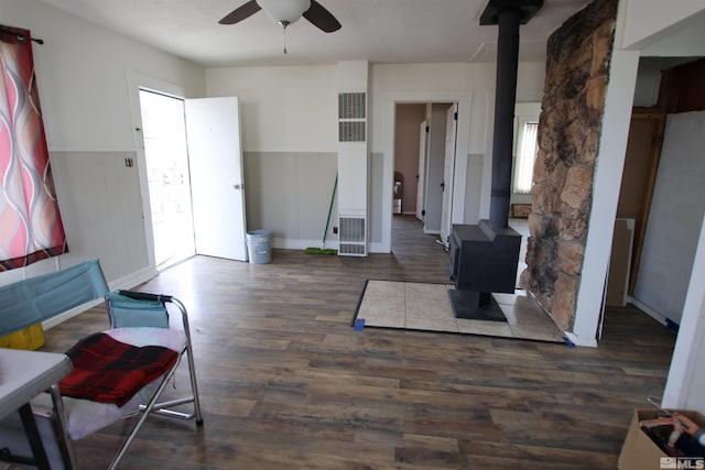 living area featuring a wood stove, a ceiling fan, and a wealth of natural light