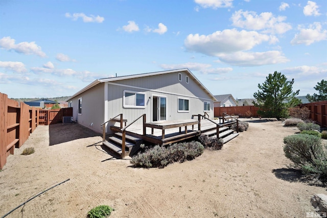 rear view of property with a fenced backyard, a wooden deck, and central AC