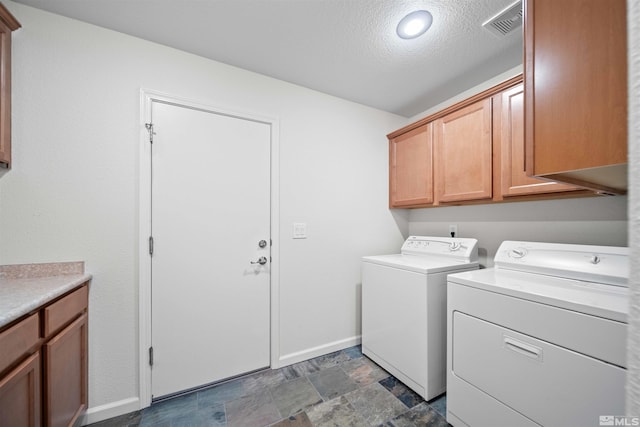washroom with washer and clothes dryer, a textured ceiling, baseboards, stone finish flooring, and cabinet space