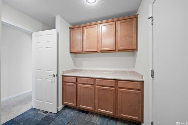 kitchen featuring light countertops, a textured ceiling, and brown cabinets