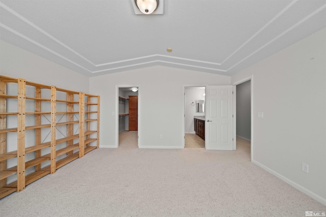 interior space with a spacious closet, vaulted ceiling, baseboards, carpet flooring, and ensuite bathroom