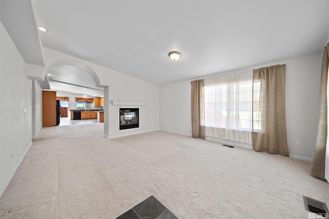 unfurnished living room with baseboards, visible vents, and light carpet