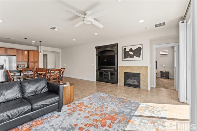 tiled living area featuring a ceiling fan, a glass covered fireplace, visible vents, and recessed lighting