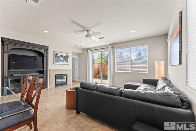 living room featuring a ceiling fan, visible vents, a tile fireplace, and light tile patterned flooring