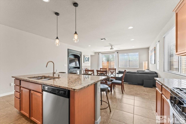 kitchen featuring an island with sink, a sink, appliances with stainless steel finishes, open floor plan, and a breakfast bar area