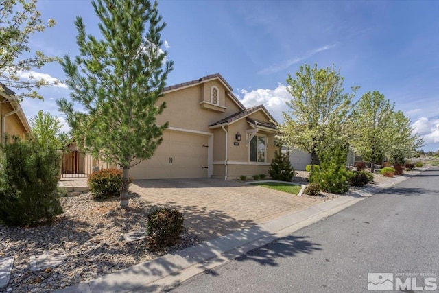 view of front of home with a tile roof, decorative driveway, an attached garage, fence, and stucco siding