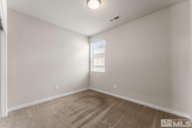 spare room featuring carpet floors, visible vents, and baseboards