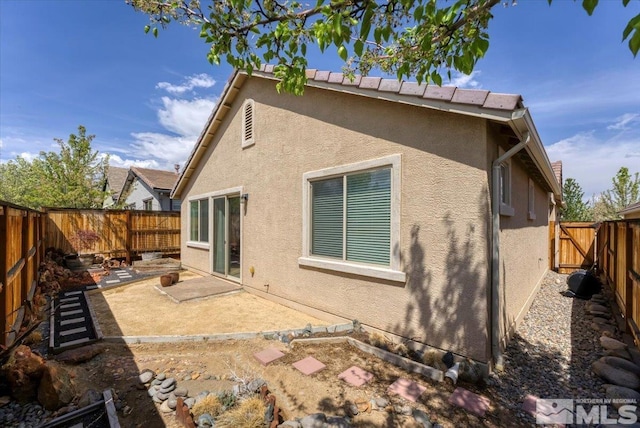 back of house featuring stucco siding, a patio area, and a fenced backyard