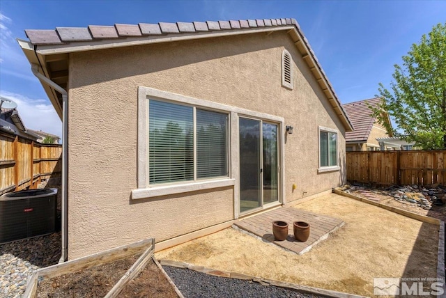 back of property with stucco siding, a patio area, a fenced backyard, and central AC unit