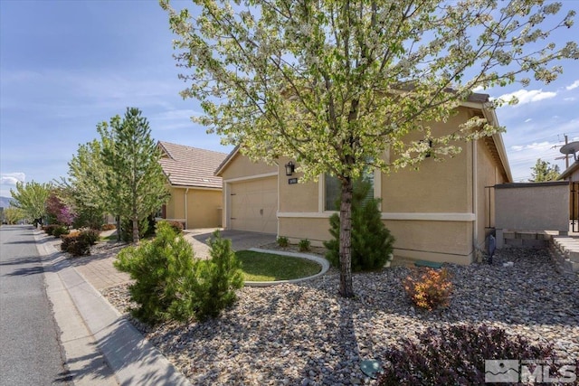 view of property hidden behind natural elements featuring stucco siding and a garage