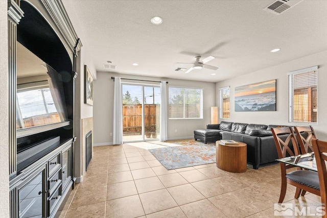 living room with visible vents, a textured ceiling, and ceiling fan