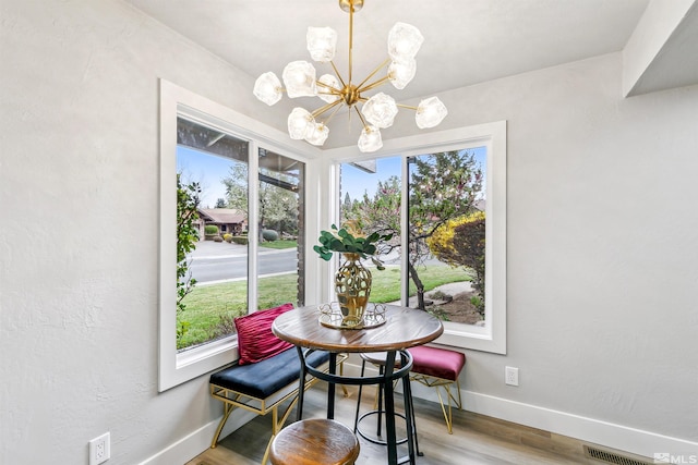 dining area with visible vents, wood finished floors, baseboards, and a chandelier