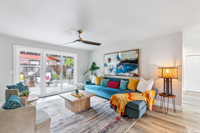 living area with wood finished floors, a ceiling fan, and baseboards