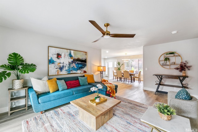 living area with baseboards, a ceiling fan, and wood finished floors