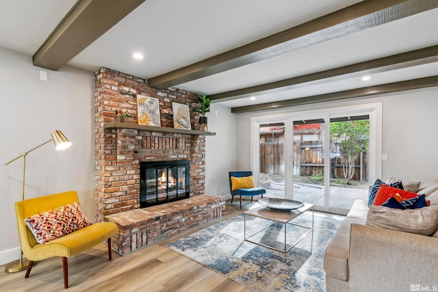 living room featuring beamed ceiling, wood finished floors, a brick fireplace, and recessed lighting
