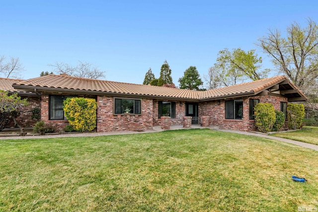 ranch-style house with a tiled roof, a front lawn, and brick siding
