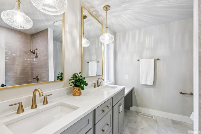 full bath featuring marble finish floor, a tile shower, a sink, and visible vents