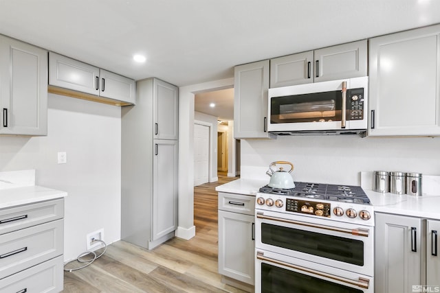kitchen with light countertops, high end white range, light wood finished floors, and recessed lighting