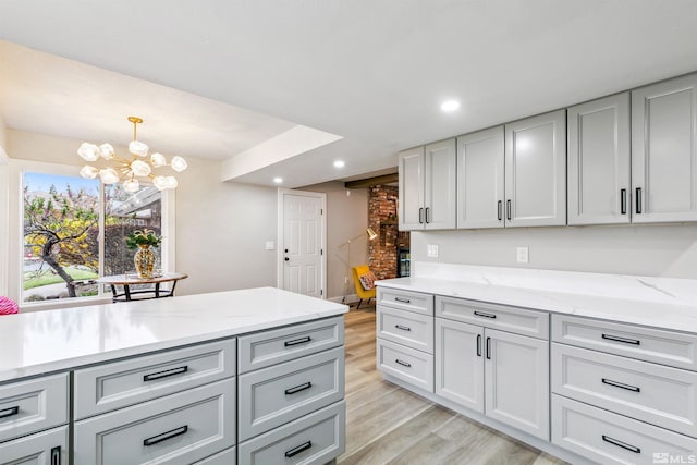 kitchen featuring light stone countertops, a chandelier, recessed lighting, and light wood-style floors