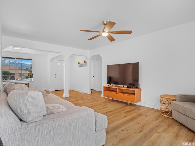 living room featuring a ceiling fan, wood finished floors, and arched walkways