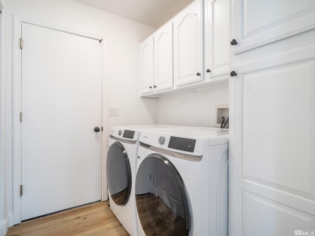 laundry room featuring cabinet space, light wood-type flooring, and washer and clothes dryer