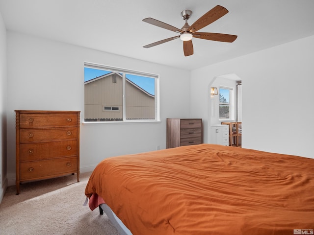 carpeted bedroom featuring a ceiling fan, baseboards, and arched walkways