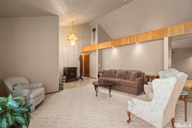 living area featuring a wood stove, high vaulted ceiling, a notable chandelier, and light colored carpet