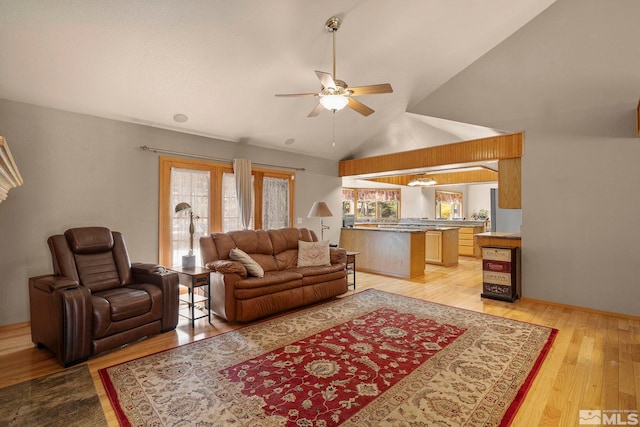 living area featuring lofted ceiling, a ceiling fan, and light wood-style floors