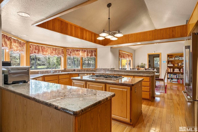 kitchen with a center island, a peninsula, a notable chandelier, and appliances with stainless steel finishes