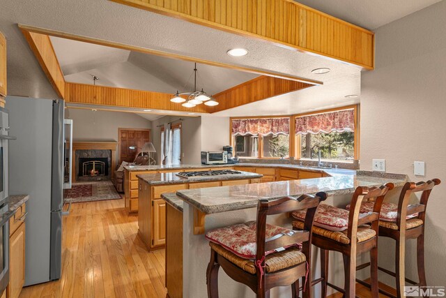 kitchen with a peninsula, a breakfast bar, stone countertops, and light wood-style floors