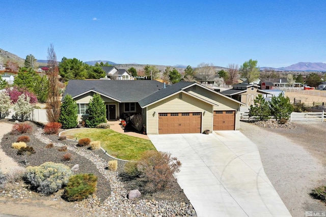 single story home featuring an attached garage, driveway, fence, and a mountain view